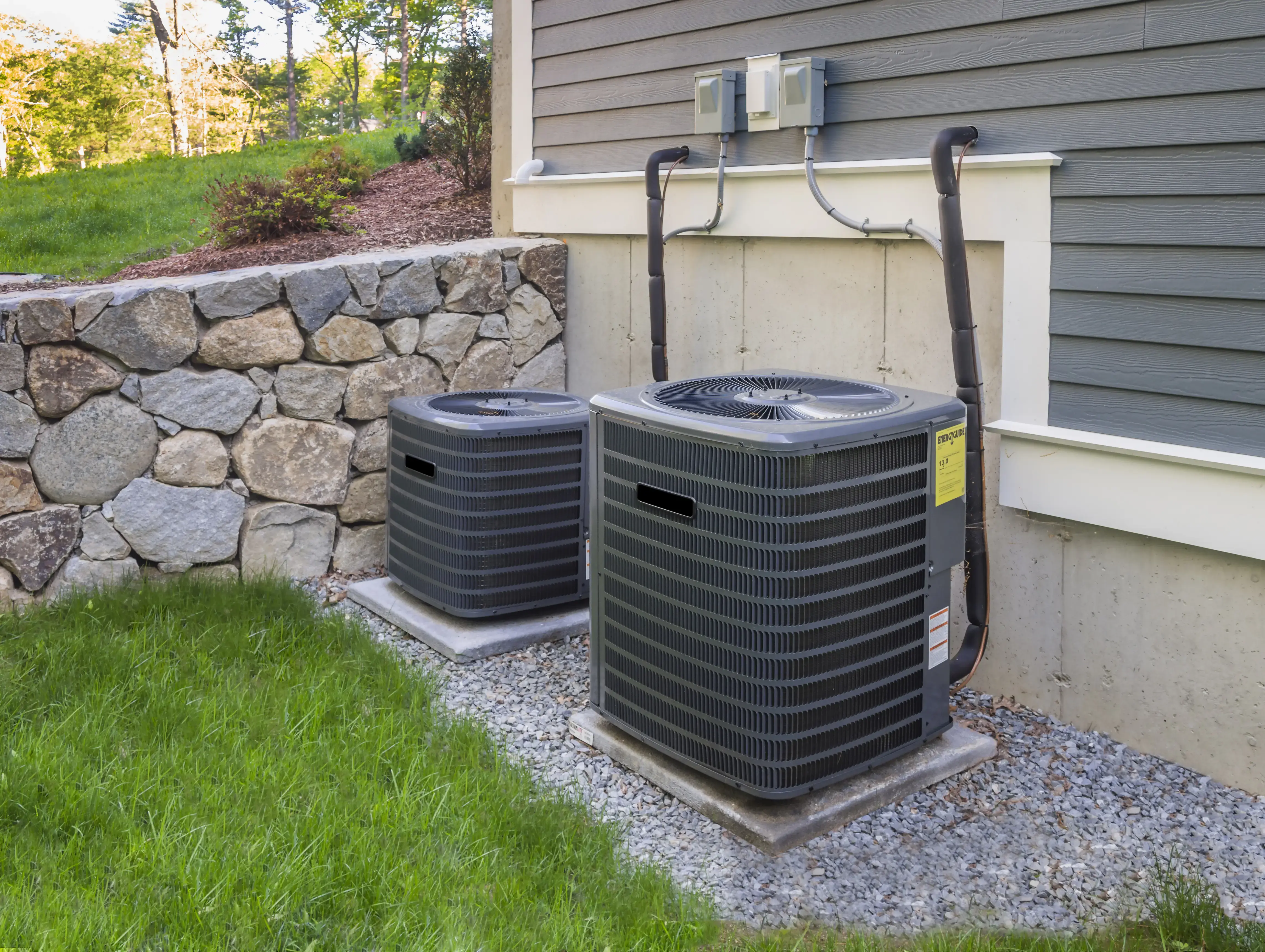 High-efficiency heat pump and air conditioning condensers installed beside a home